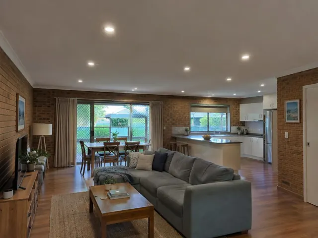 Open-plan living room and kitchen with recessed LED downlights in a brick-walled home in Kincumber
