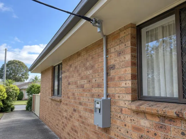 Brick house exterior with new overhead service cable, point-of-attachment bracket and meter box in Erina